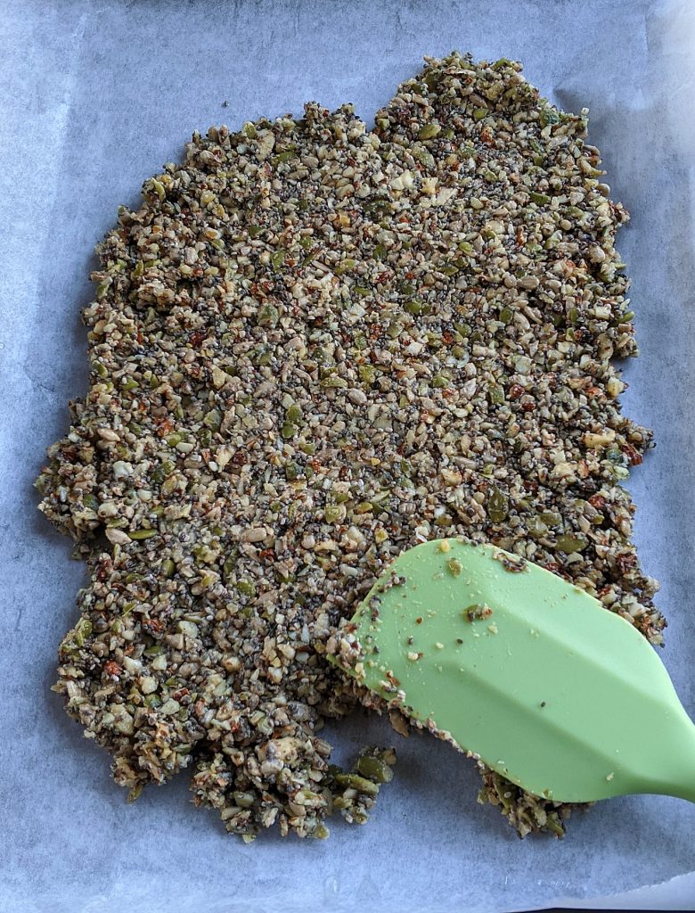 Spreading the Keto Mixed Nut Granola Bites on a baking tray covered with parchment paper