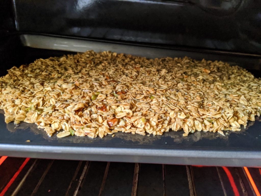 The finished Wholesome Maple Nut Breakfast Granola spread onto a baking tray and in the oven