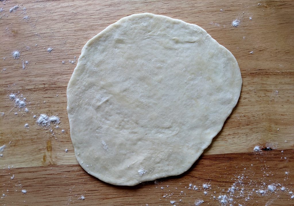 A fully flattened piece of homemade tortilla dough