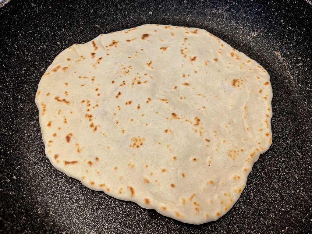 Flipped over tortilla dough with browning spots