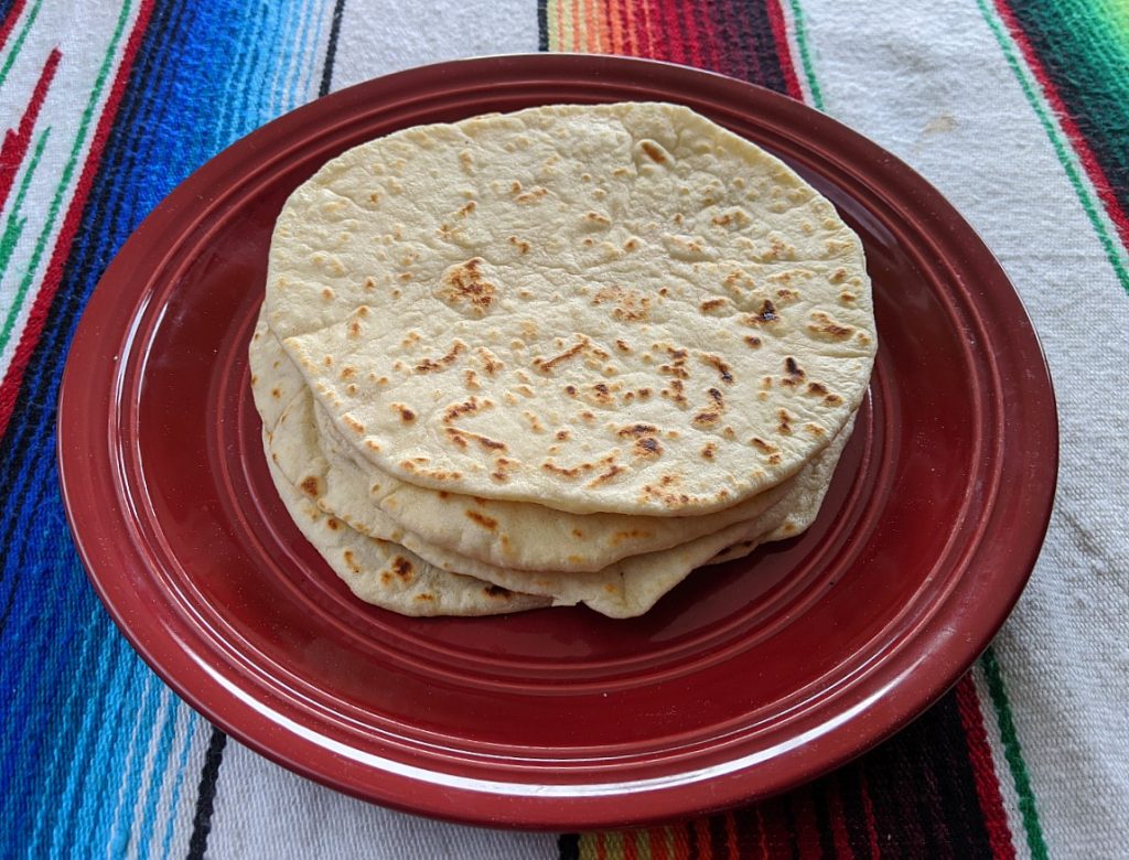 Stack of homemade flour camping tortillas on red plate