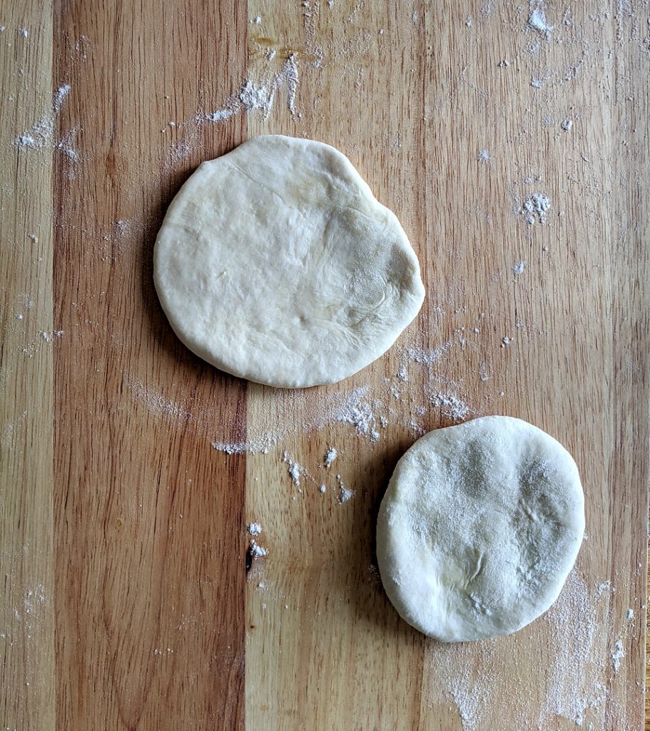 Two partially flattened pieces of homemade tortilla dough