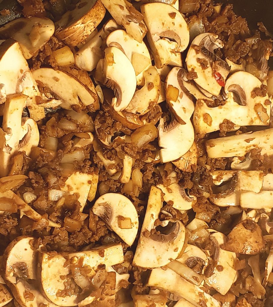 Close up of mushrooms, TVP, onions and garlic cooking in a pan